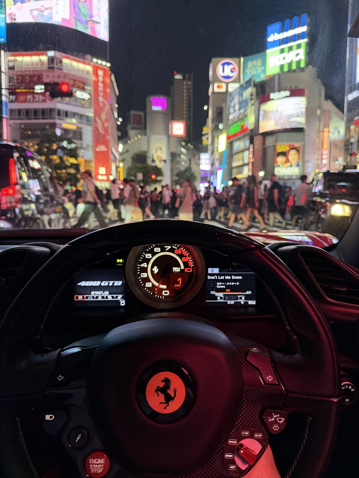 Shibuya Scramble Crossing seen at night through the windscreen of the Ferrari 488 GTB from the passenger seat