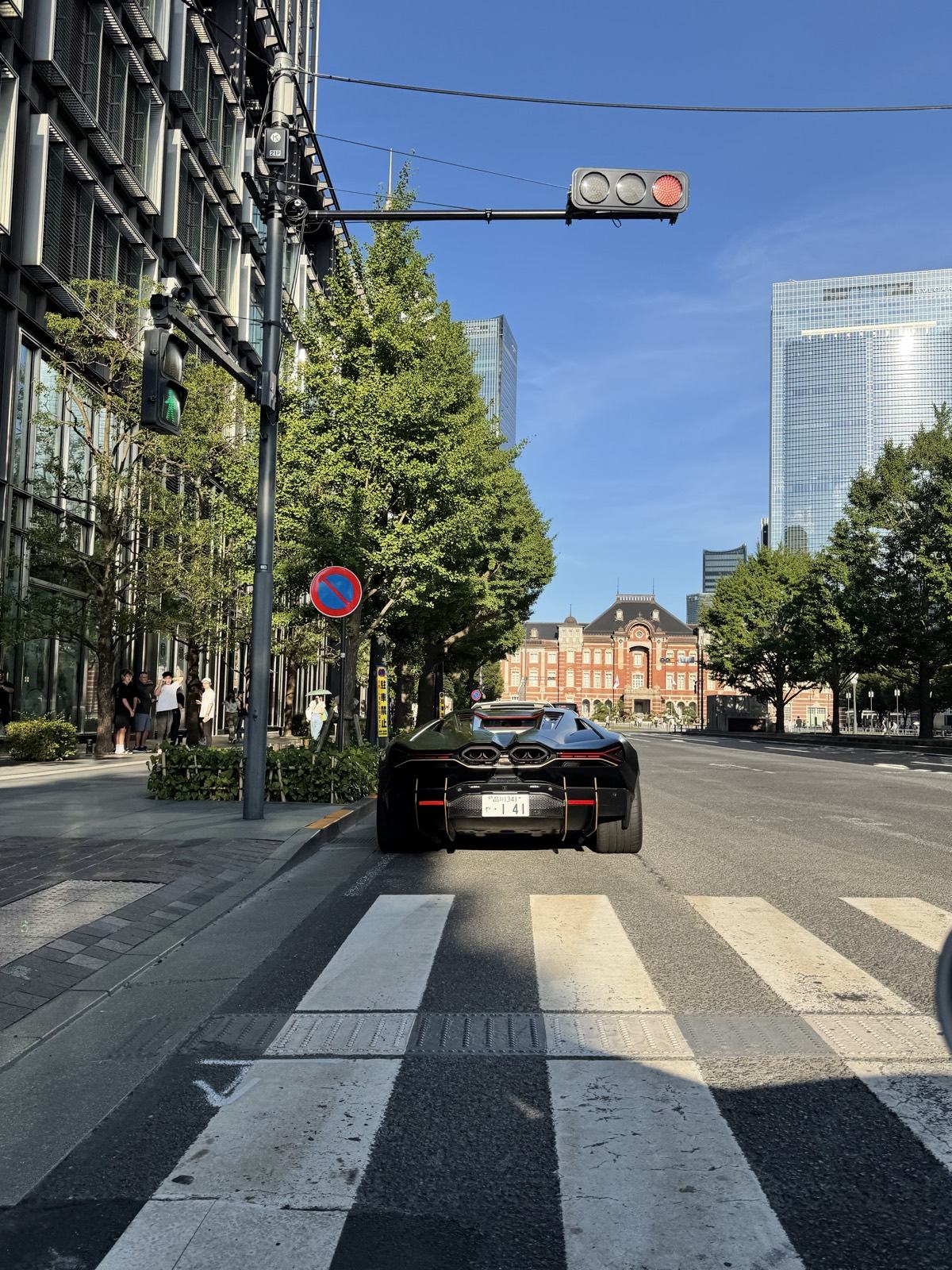 Black Lamborghini Revuelto on Gyoko-dori avenue in front of the red brick facade of Tokyo Station