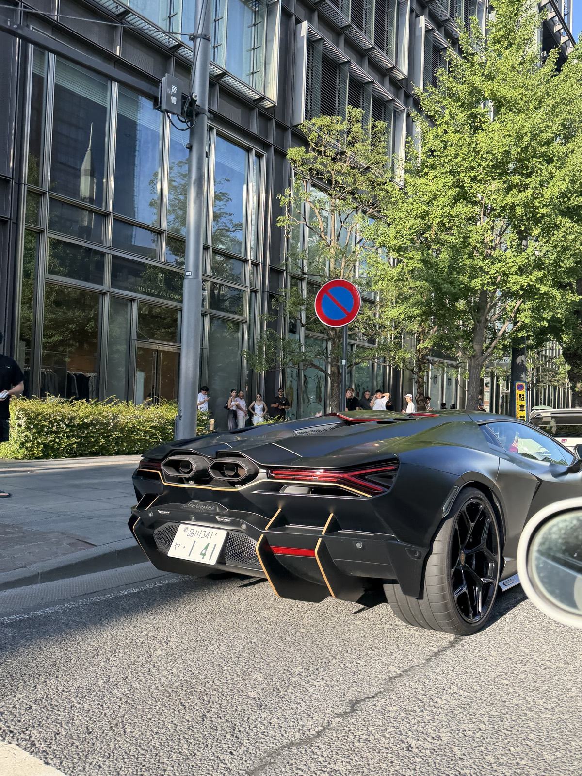 Rear view of the black Lamborghini Revuelto showing its hexagonal centre-exit exhausts, parked on a Marunouchi street in Tokyo